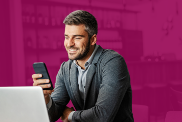 Man on cell phone in front of laptop